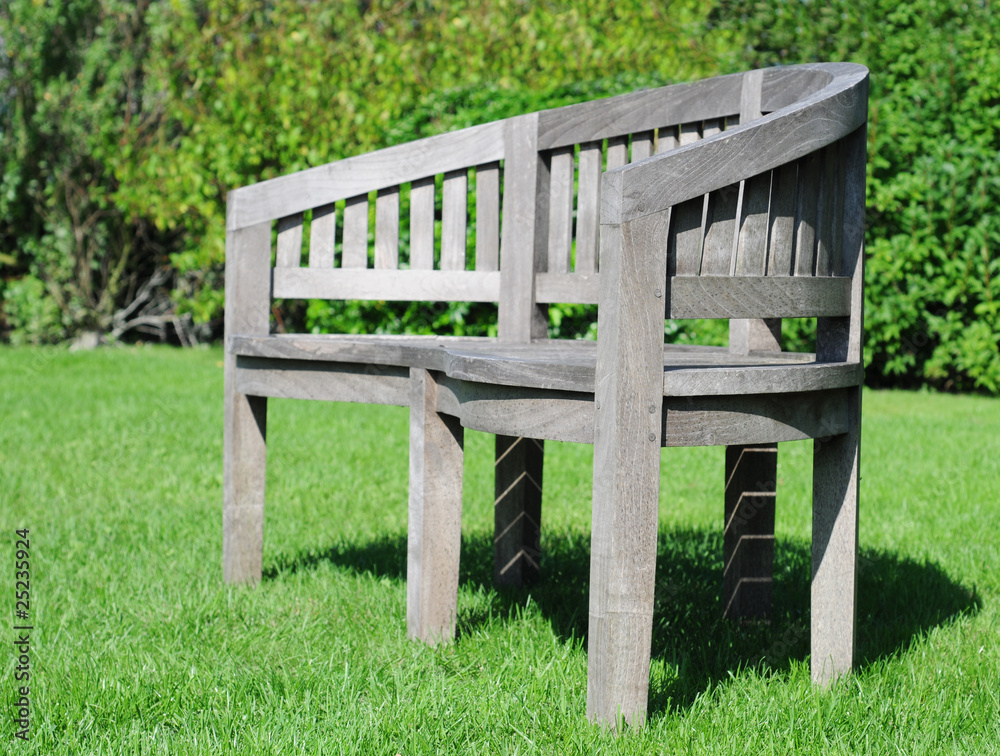 Teak garden seat in the grass, shallow dof