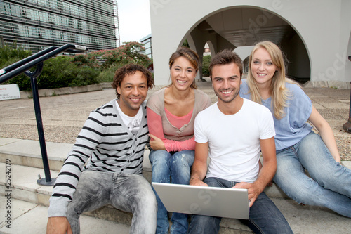 Friends sitting in college campus with laptop computer photo