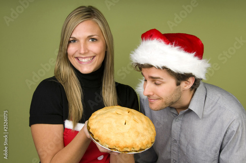 Man smelling pie held by woman