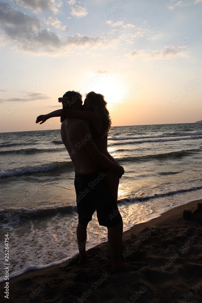 Foto Stock coppia di innamorati sulla spiaggia che si bacia | Adobe Stock