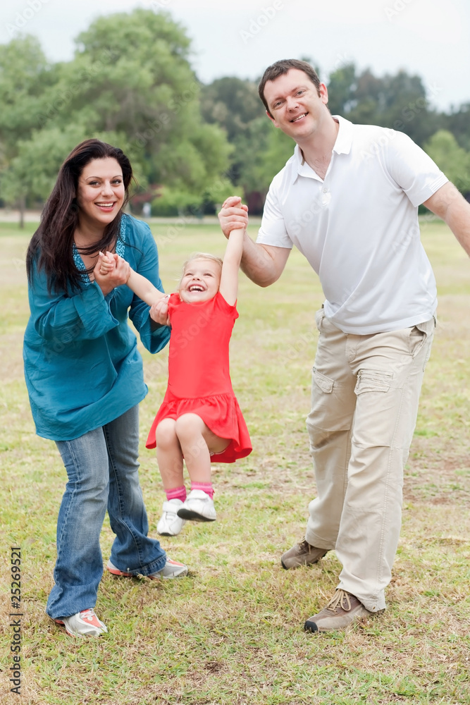 Lovely couples playing with their happy daughter at the park Lovely couples playing with their happy daughter at the park