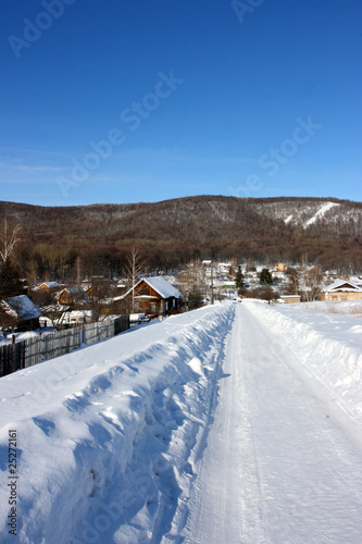 Winter village road against mountains and a blue sky