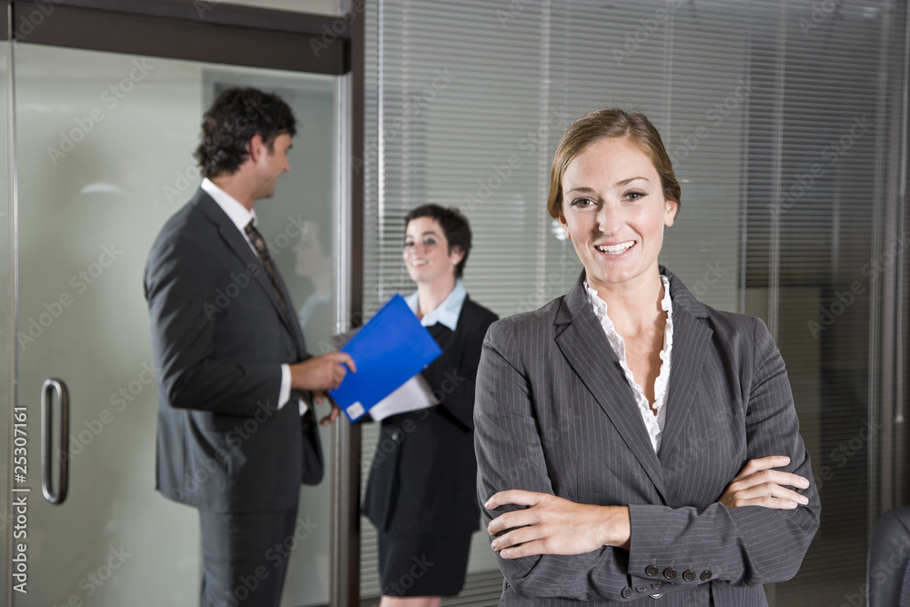 Confident businesswoman, colleagues in background Confident businesswoman, colleagues in background