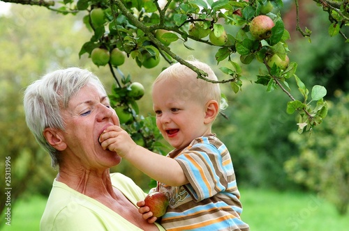 Grandmother with child under apple tree photo