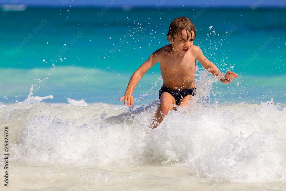 young boy enjoys playing on the waves in a tropical sea young boy enjoys playing on the waves in a tropical sea