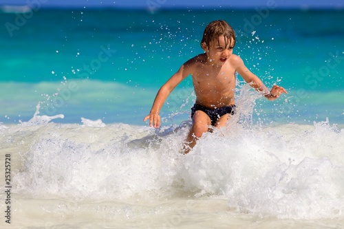young boy enjoys playing on the waves in a tropical sea © serafino