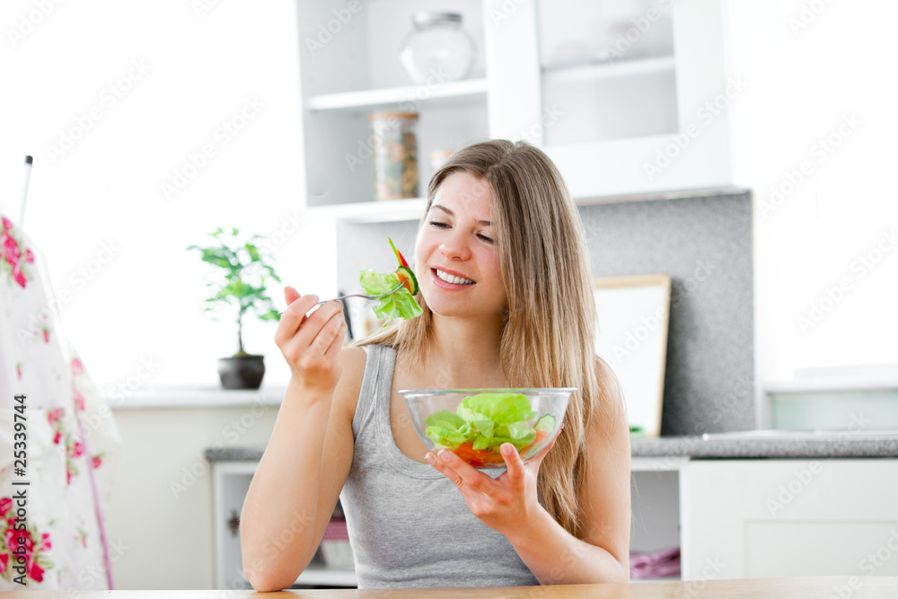 Charming woman eating a salad in the kitchen