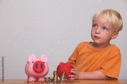 Kleiner Junge füllt sein Sparschwein