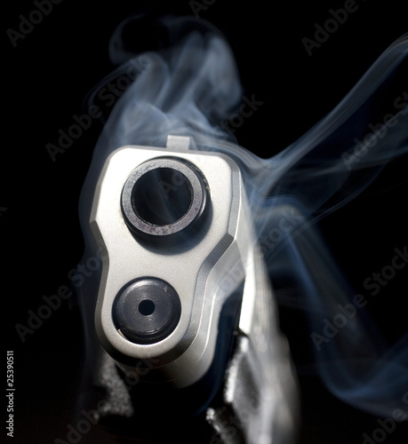 Smoking barrel of a semi-automatic pistol on a black background