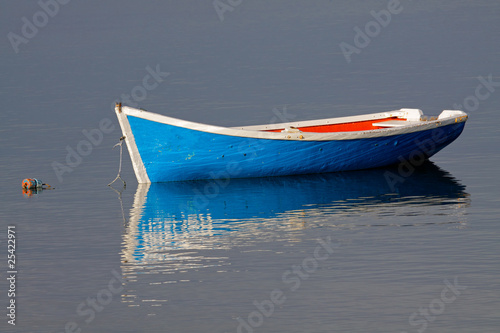 Wooden fishing boat with reflection in water