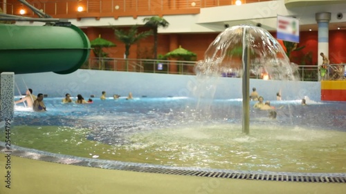 People bathe in pool with a fountain in indoor water park photo