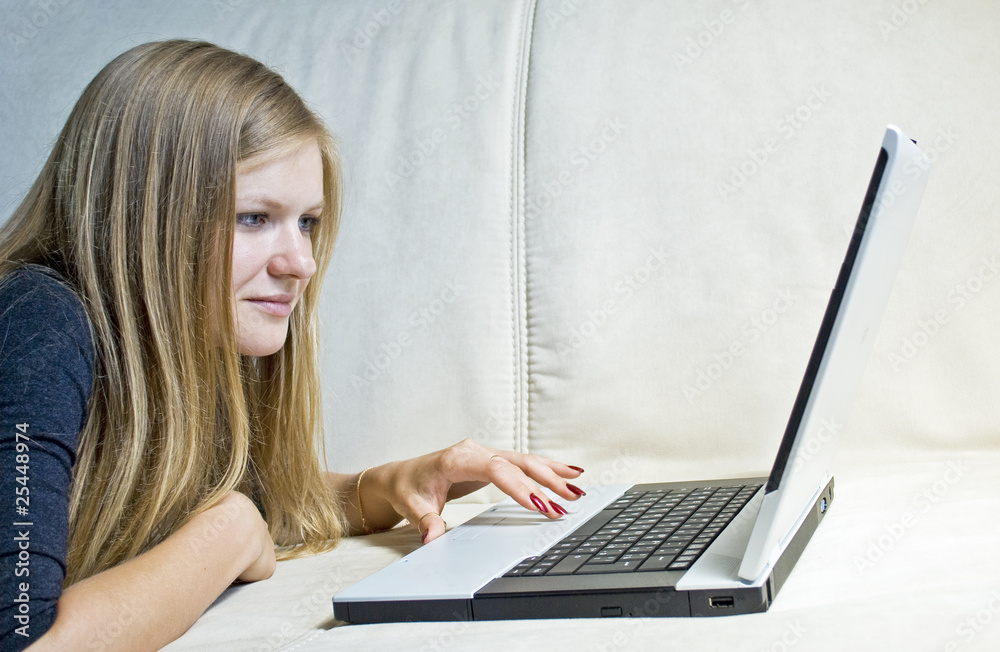 Girl lying on the couch and chatting in her notebook Girl lying on the couch and chatting in her notebook
