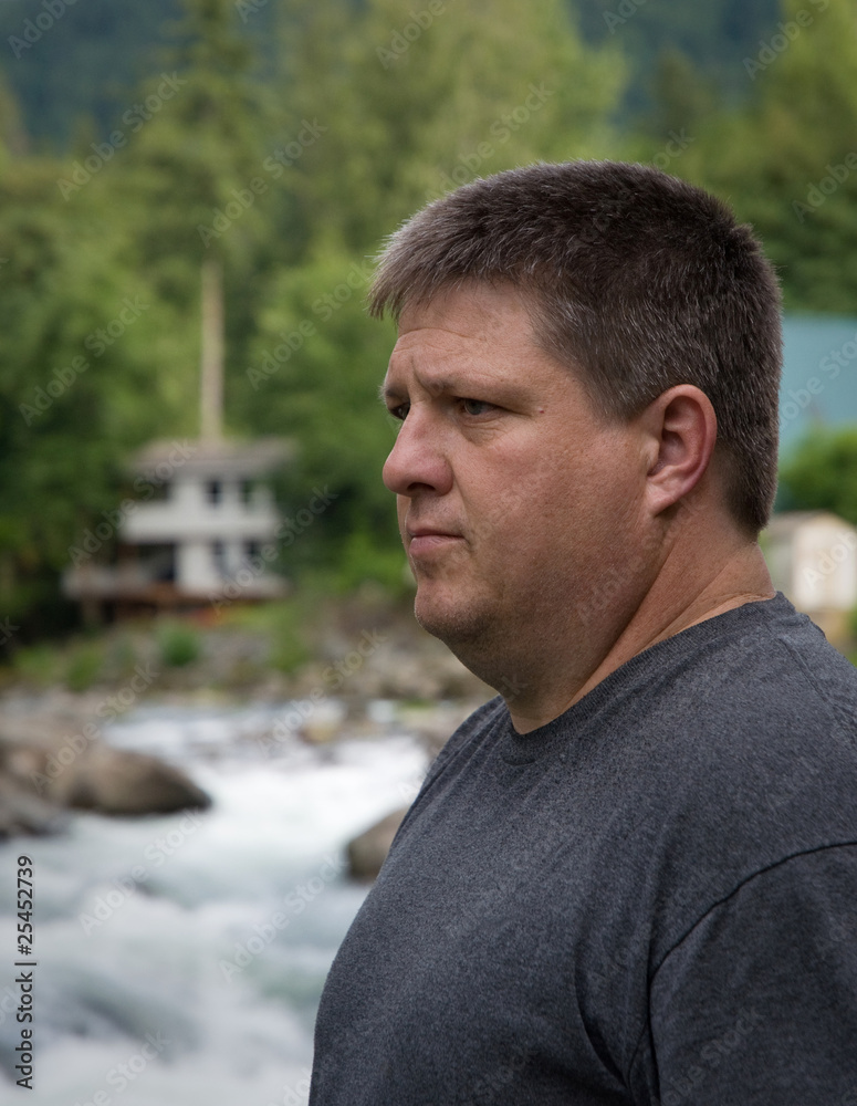 Regular guy meditating and thinking near the river Regular guy meditating and thinking near the river