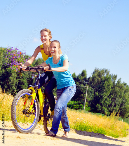 Beautiful smiling girls walk up the hill with bicycle on village