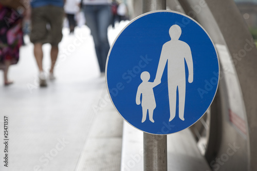 Pesdestrian sign with people walking in the background photo