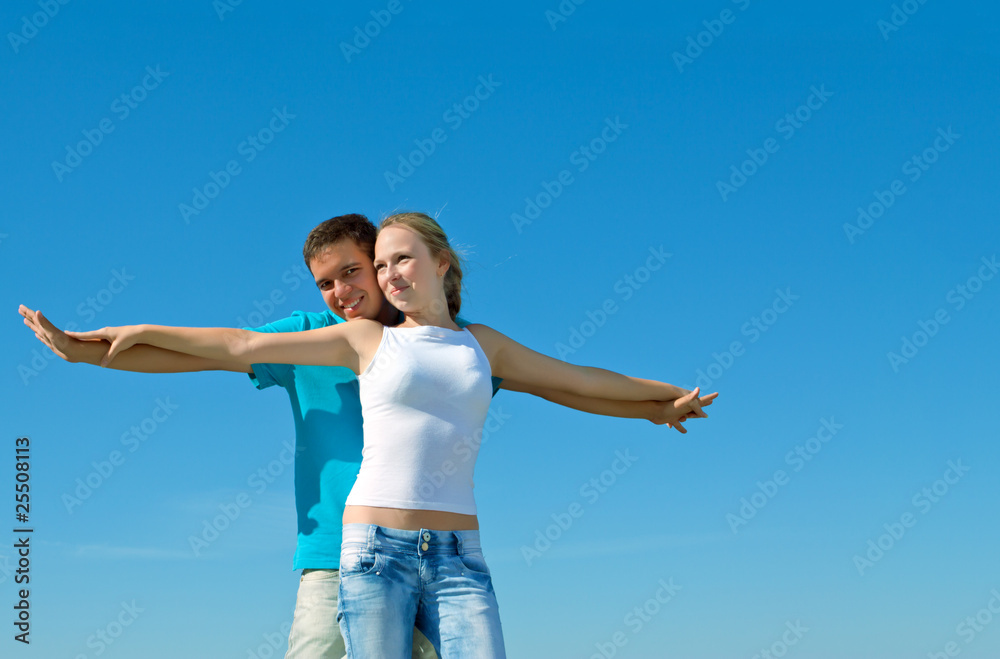 young beautiful couple embracing against blue sky young beautiful couple embracing against blue sky