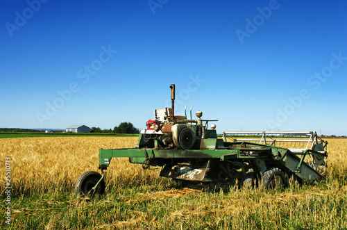 Old rusted combine harvester and barley field