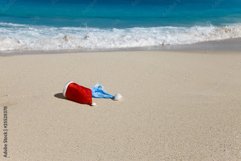 Two New Year's caps of Santa Claus on beach Two New Year's caps of Santa Claus on beach