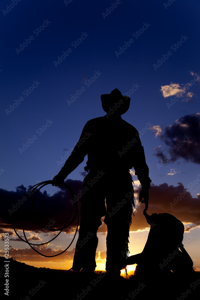 Cowboy with saddle on ground