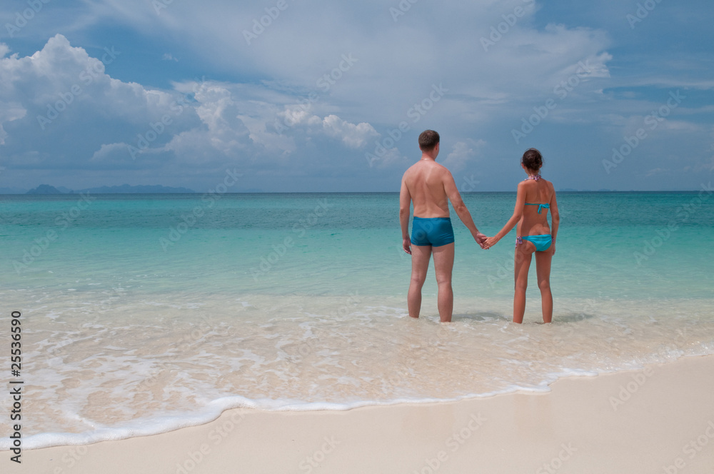 Young couple standing on a sandy tropical beach