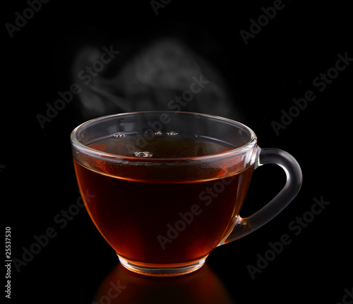 Glass cup of tea with vapor isolated on black