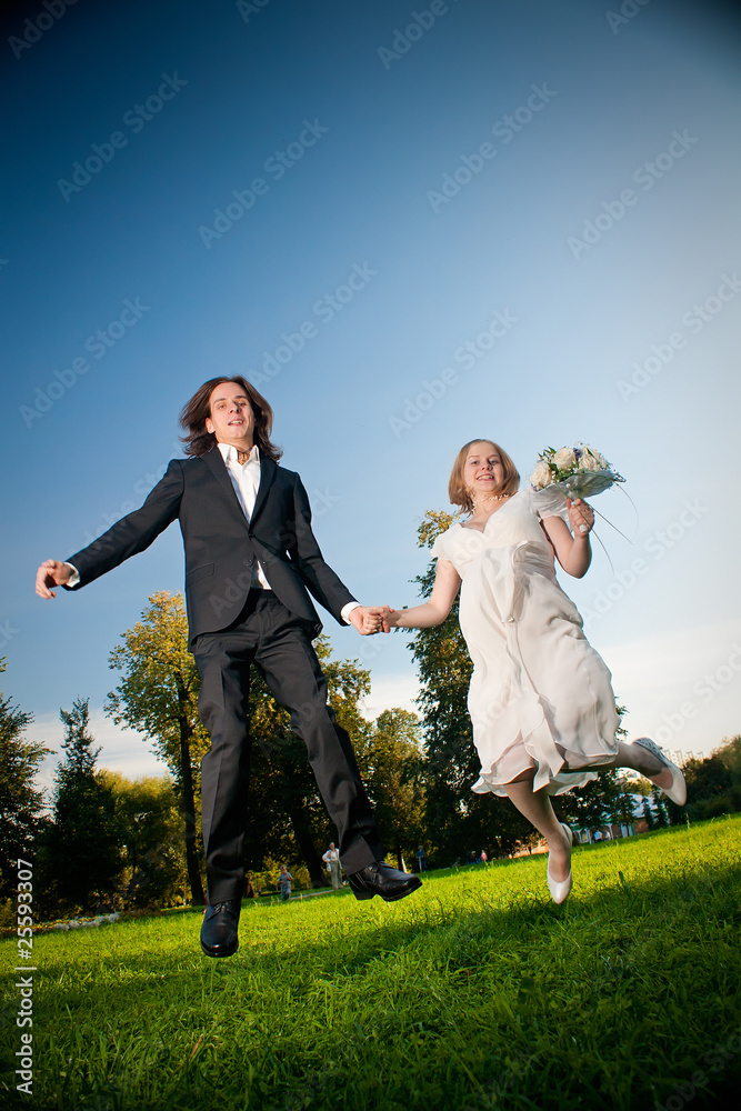 young wedding lovely couple jump in park with flowers