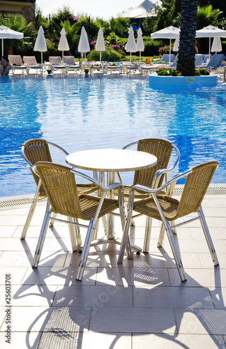 table and chairs near a cool pool in a hot canicular day