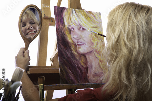 Vászonkép blond female artist in her fifties painting self portrait
