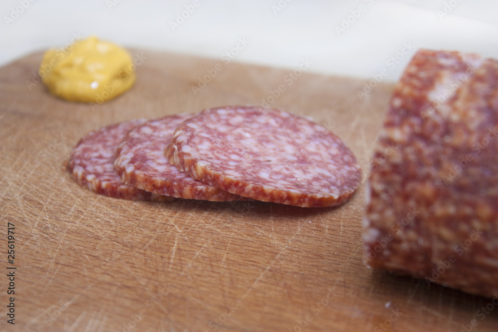 Sliced salami with mustard on wooden board Sliced salami with mustard on wooden board