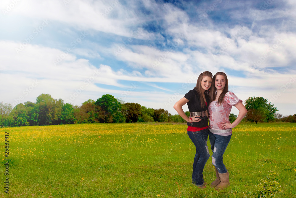 Two pretty teen girls standing in wildflower meadow.
