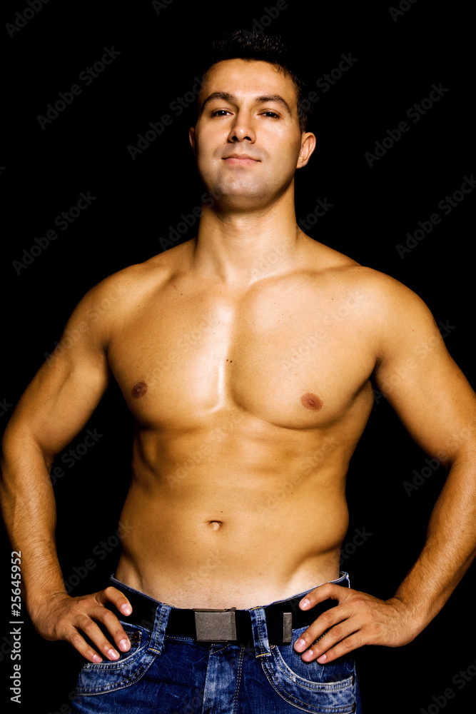 Fototapeta premium Young man with atletic body on black background