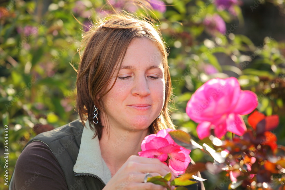 Obraz premium Junge attraktive Frau genießt den Duft einer Rose