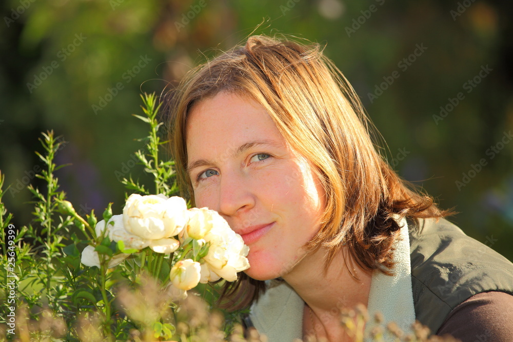 Junge attraktive Frau genießt den Duft einer Rose Junge attraktive Frau genießt den Duft einer Rose