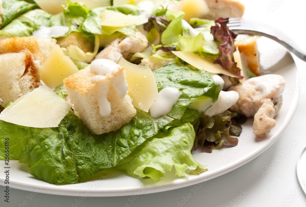traditional caesar salad on white plate with a fork traditional caesar salad on white plate with a fork