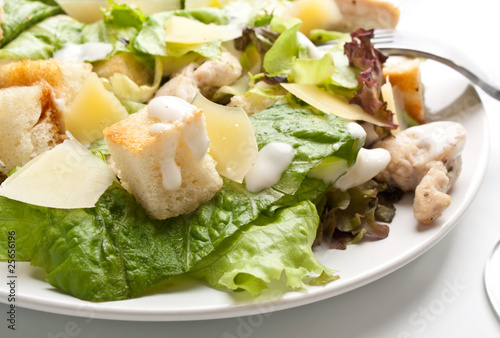 traditional caesar salad on white plate with a fork