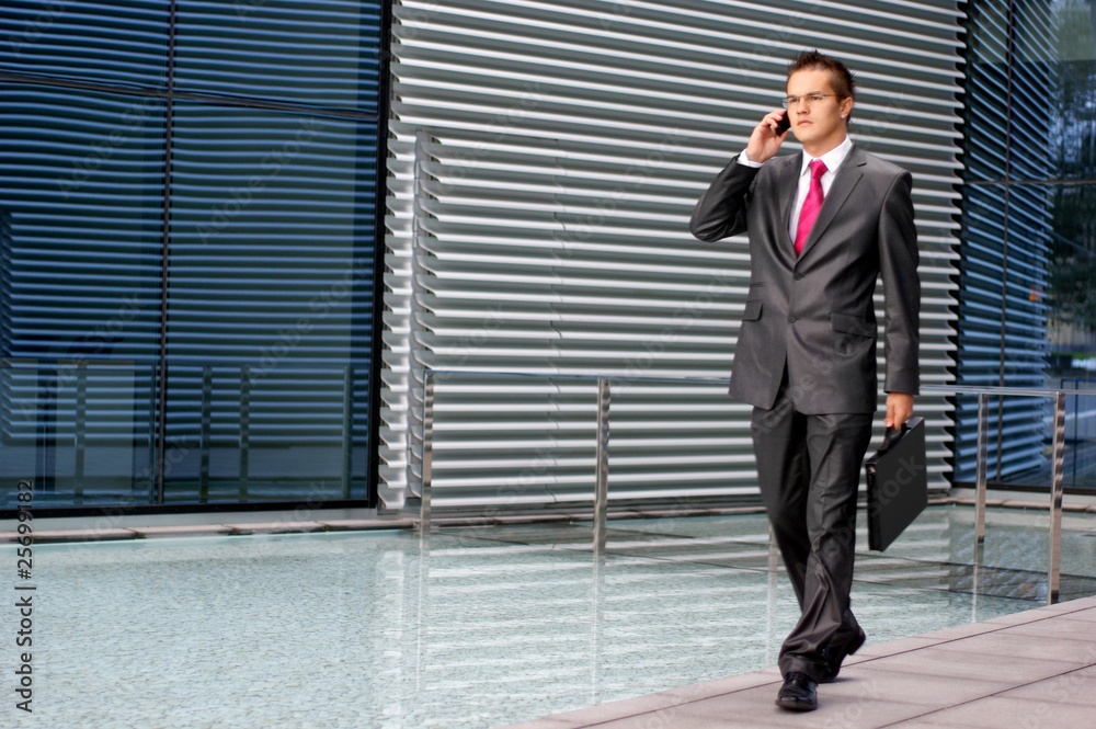 A young business man is talking on the phone A young business man is talking on the phone