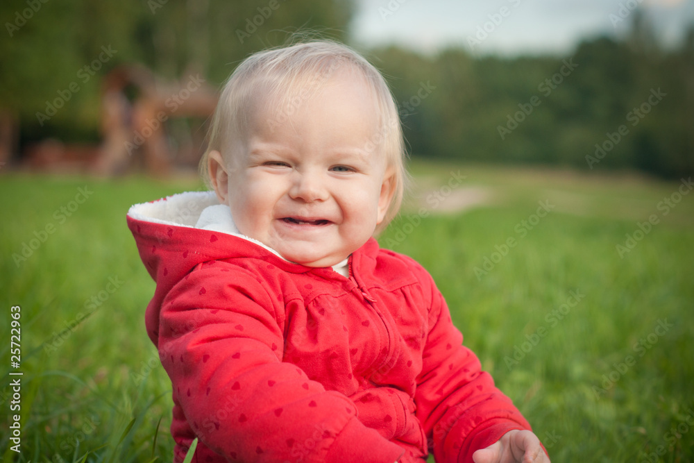 adorable baby sit on green grass near forest within red jacket adorable baby sit on green grass near forest within red jacket