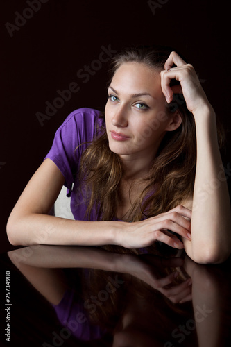 Portrait of young woman sitting at glossy table