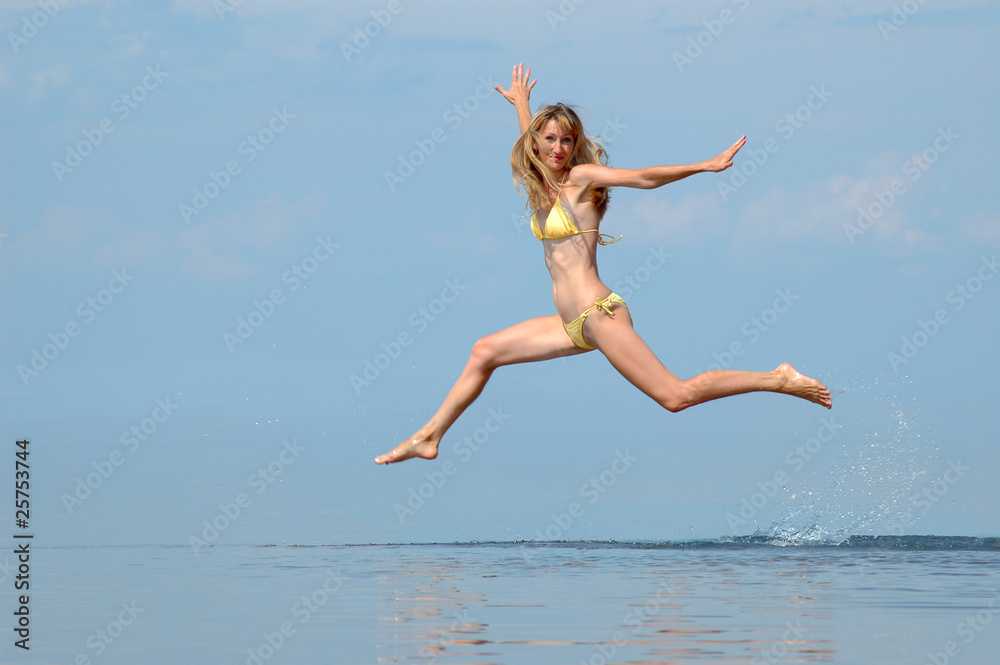 Naklejka premium The woman in a bathing suit jumps on water