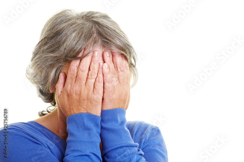 Seniorin hält sich Hände vor Gesicht