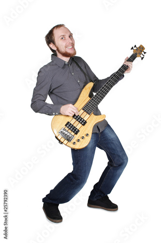 young man with beard in grey shirt and jeans playing bass guitar