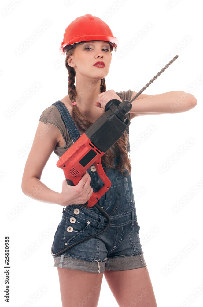 Young playful woman in jeans coverall holding perforator drill Young playful woman in jeans coverall holding perforator drill