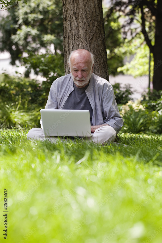 homme retraité travaillant avec pc dans jardin homme retraité travaillant avec pc dans jardin