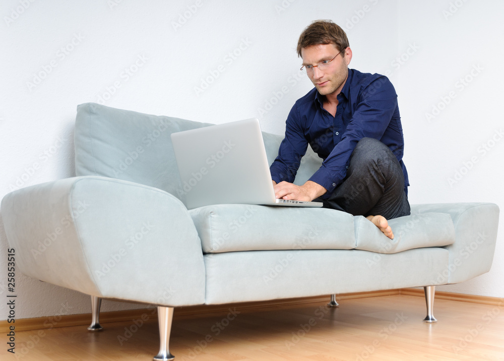 Young man relaxing with laptop on a couch Young man relaxing with laptop on a couch