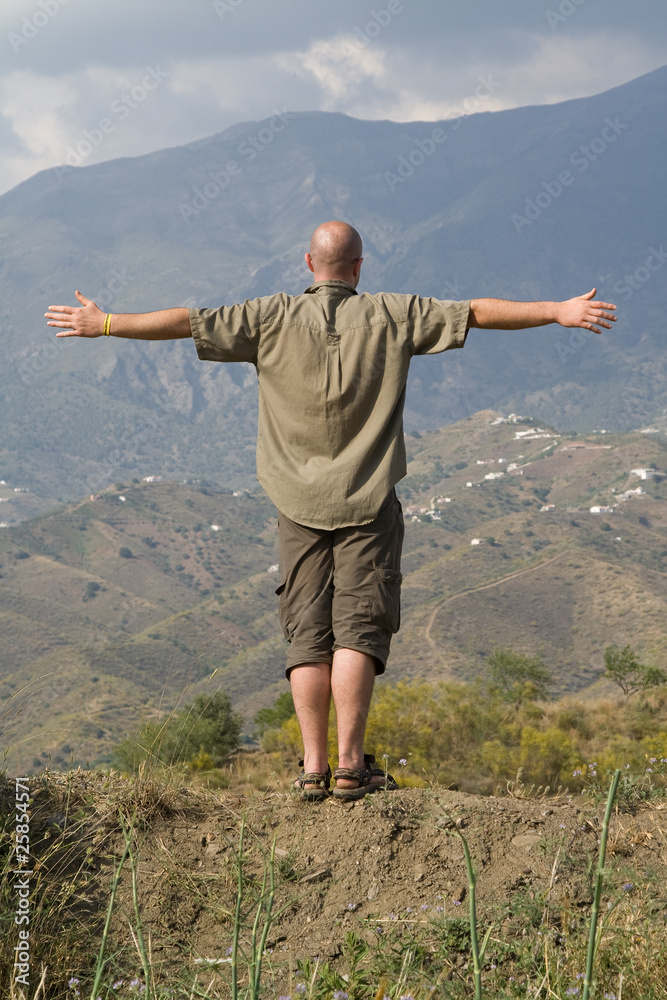 Silhouette of a man with arms spread out on the mountain's edge