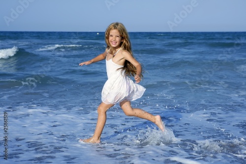 Little girl running beach in blue sea photo