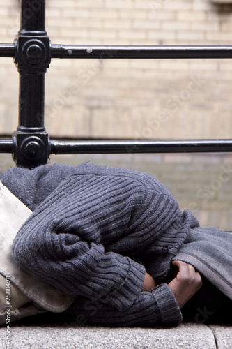 homeless man lying in street with shadowed out face 