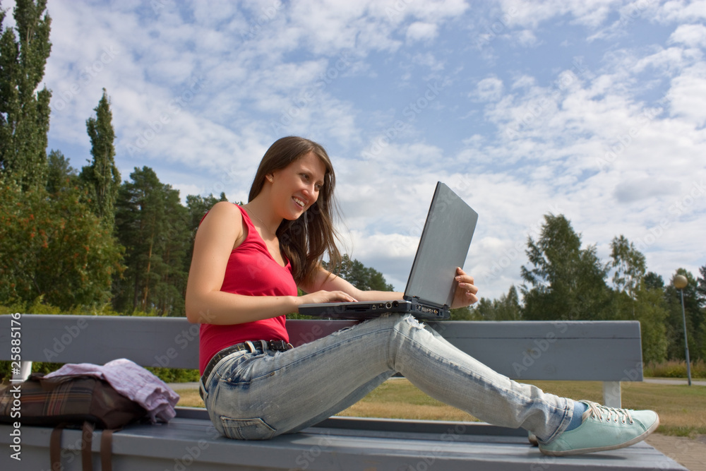 Young businesswoman working on laptop outdoor