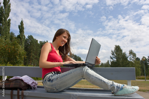 Young businesswoman working on laptop outdoor