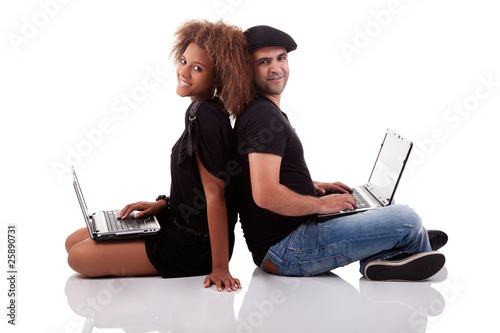 Couple back to back, sitting on the floor, with computers
